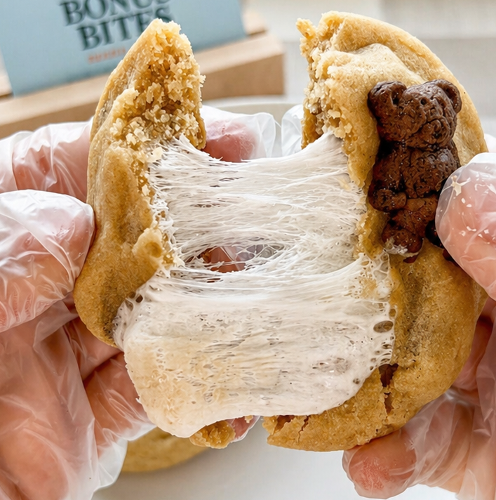 Stuffed s’mores cookie pulled apart with gooey marshmallow center and melted chocolate chips on white plate